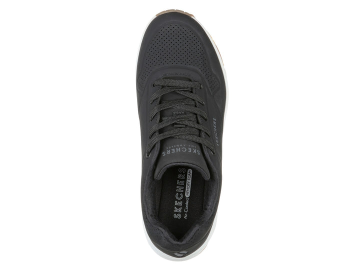 Tenis deportivos Skechers color negro con suela blanca y amortiguación visible en el talón.