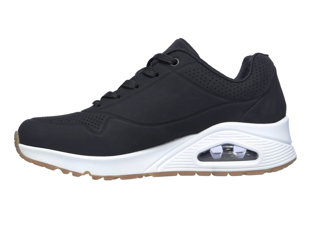 Tenis deportivos Skechers color negro con suela blanca y amortiguación visible en el talón.