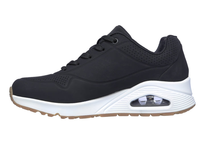 Tenis deportivos Skechers color negro con suela blanca y amortiguación visible en el talón.