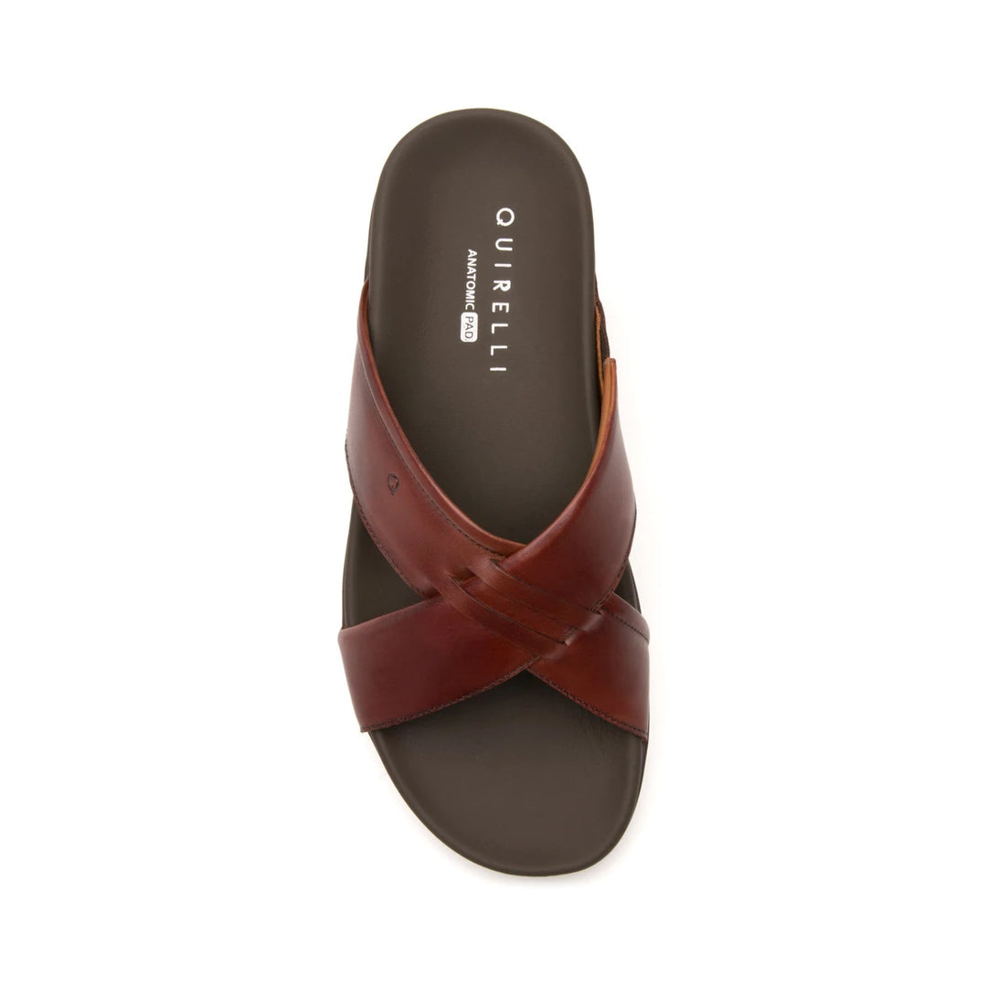 Sandalia plana de cuero color vino con diseño de tiras cruzadas y suela negra.