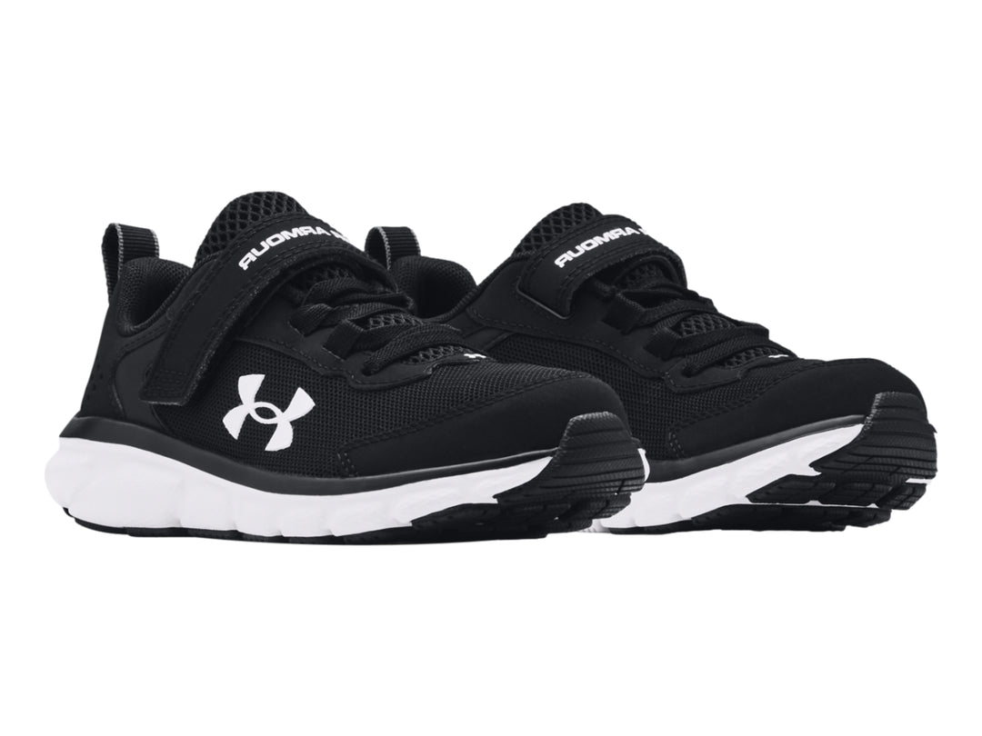 Tenis deportivos Under Armour color negro con suela blanca y correa de ajuste.