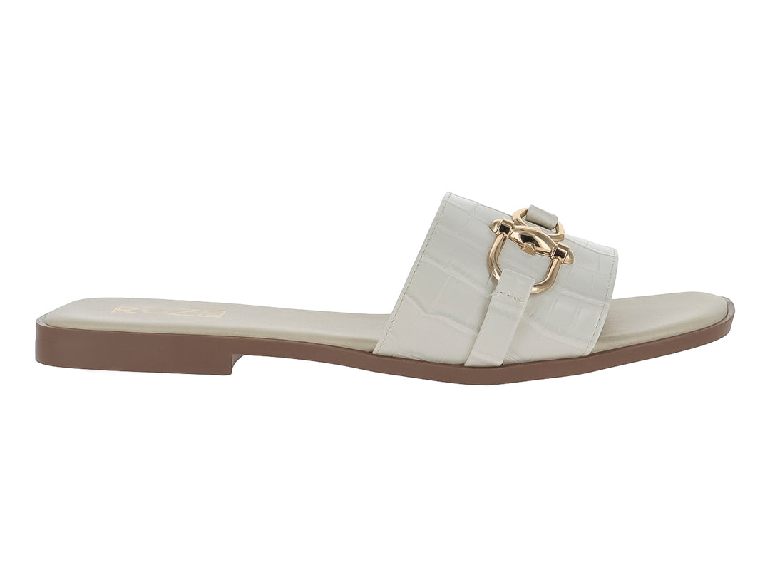 Sandalia plana color beige con textura de cocodrilo y hebilla dorada decorativa.