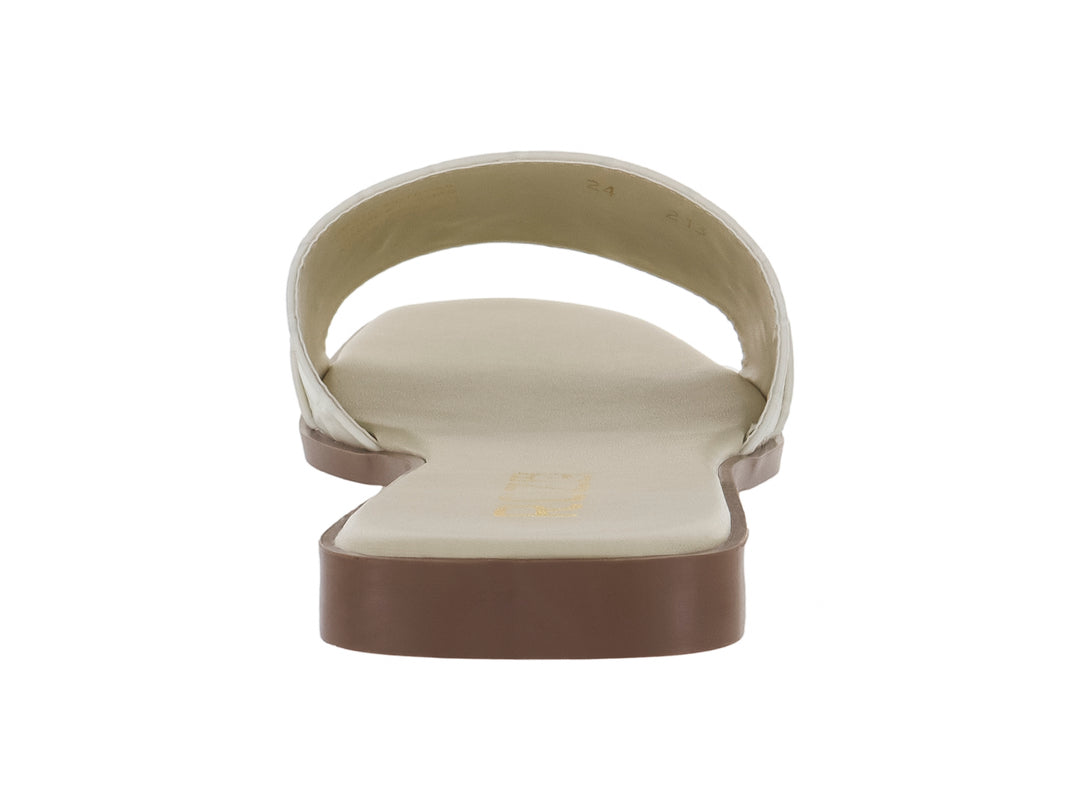 Sandalia plana color beige con textura de cocodrilo y hebilla dorada decorativa.