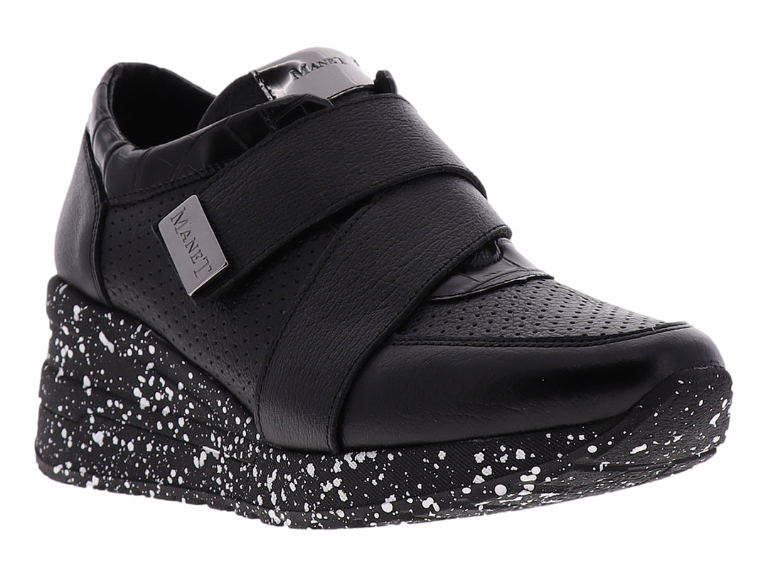 Zapato confort negro para mujer con suela blanca moteada y correa decorativa con logo MANET.