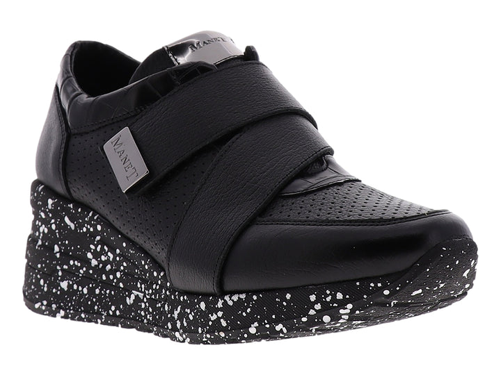 Zapato confort negro para mujer con suela blanca moteada y correa decorativa con logo MANET.