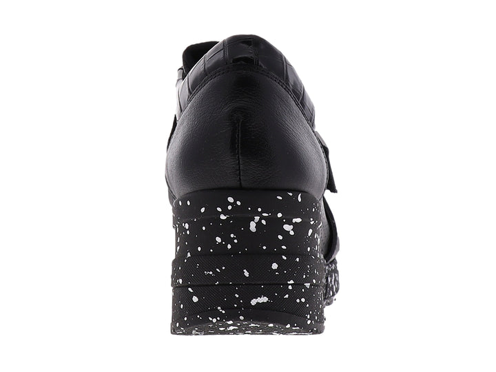 Zapato confort negro para mujer con suela blanca moteada y correa decorativa con logo MANET.
