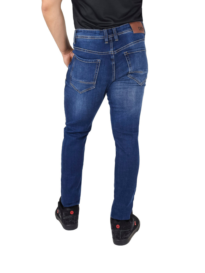 Hombre vistiendo pantalones jeans azul stone con efecto de destrucción y corte ajustado.