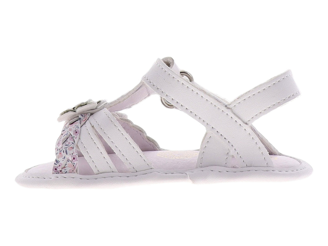 Sandalia blanca para bebé con detalle de flor plateada y brillante en la parte superior.