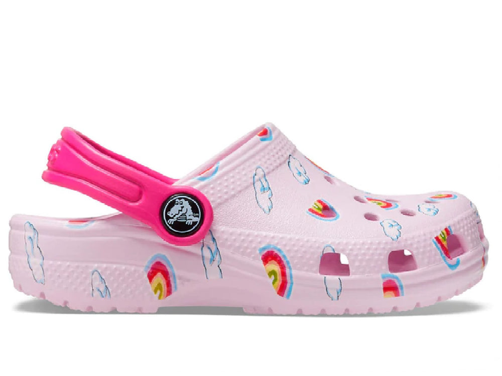 Zuecos Crocs color rosa para niña con diseño de arcoíris y nubes y correa rosa fuerte.