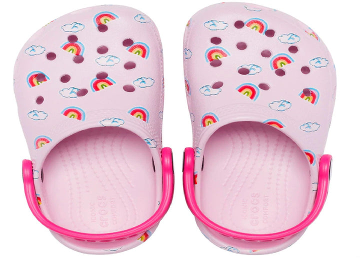 Zuecos Crocs color rosa para niña con diseño de arcoíris y nubes y correa rosa fuerte.