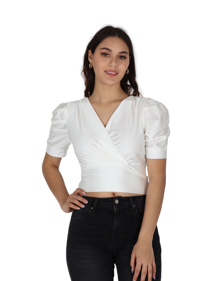 Mujer vistiendo blusa color ivory con cuello en V, cruce frontal y mangas bombacha cortas.