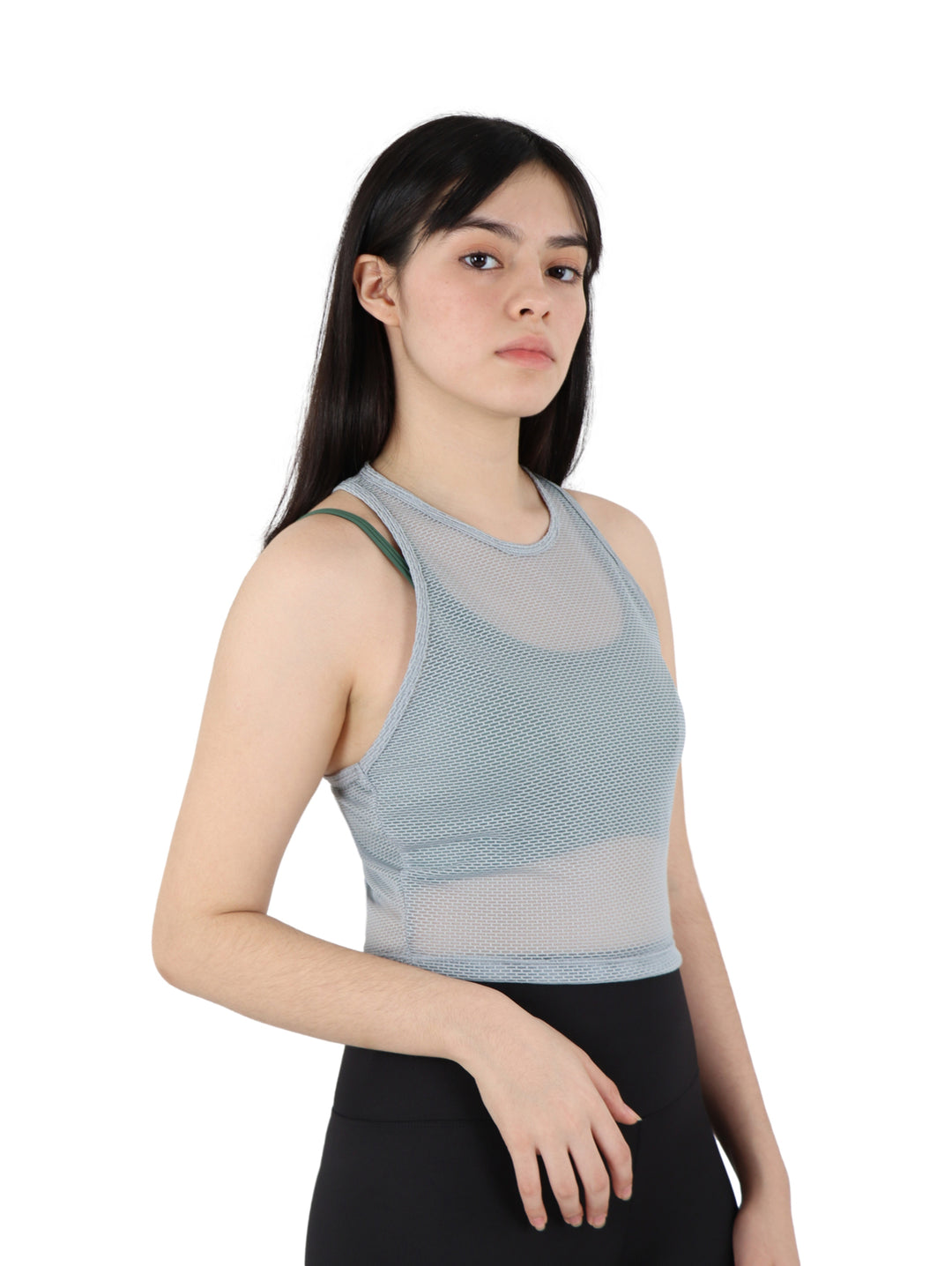 Mujer vistiendo un top crop deportivo gris perforado y leggings negros sobre fondo blanco.
