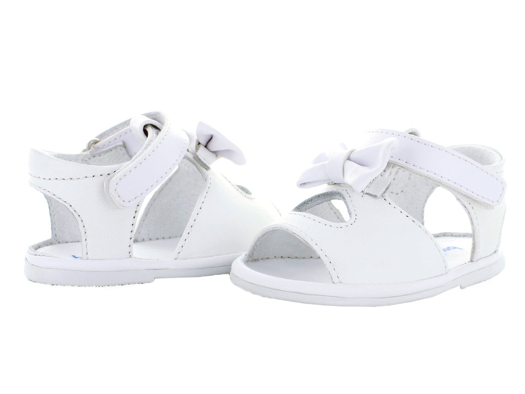 Par de sandalias blancas para bebé con moño decorativo y correa ajustable.