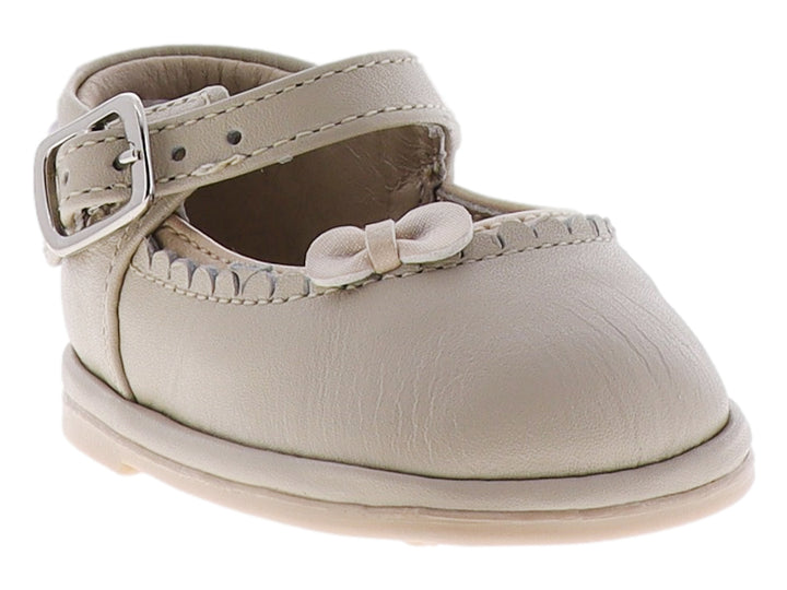 Zapato para bebé color hueso con moño frontal y correa con hebilla metálica.