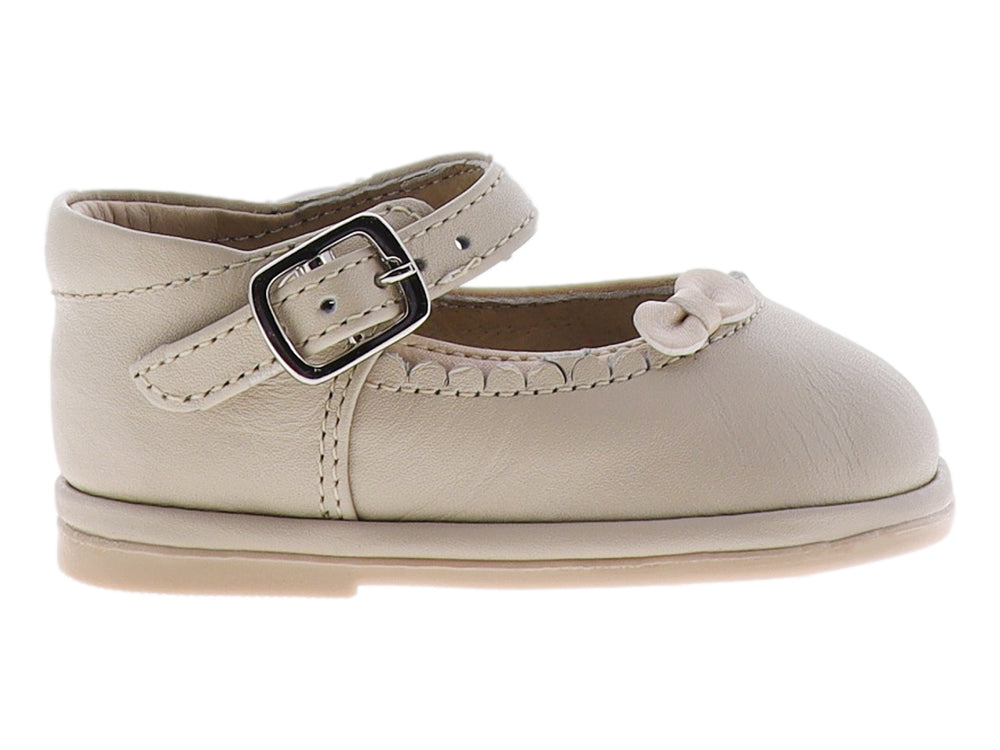 Zapato para bebé color hueso con moño frontal y correa con hebilla metálica.
