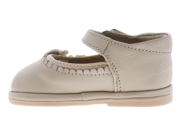 Zapato para bebé color hueso con moño frontal y correa con hebilla metálica.