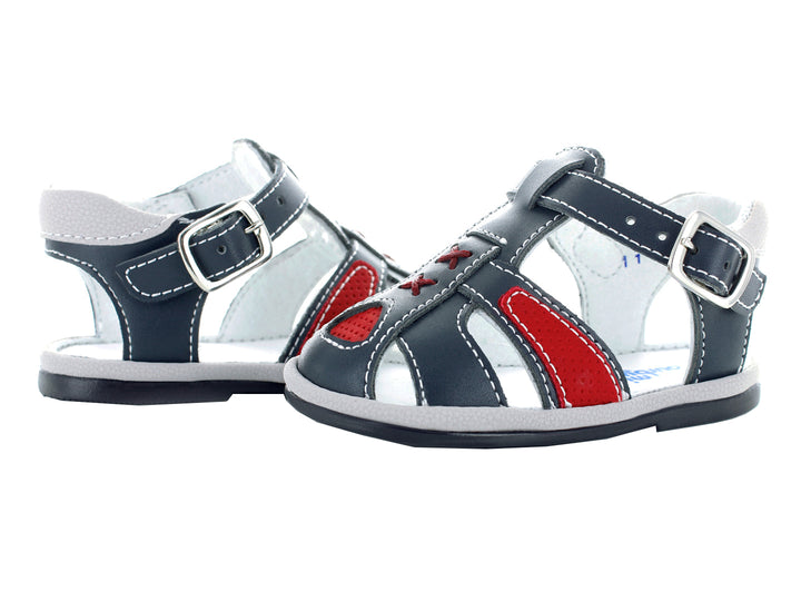 Sandalias infantiles cerradas color azul marino con detalles rojos y cierre de hebilla.