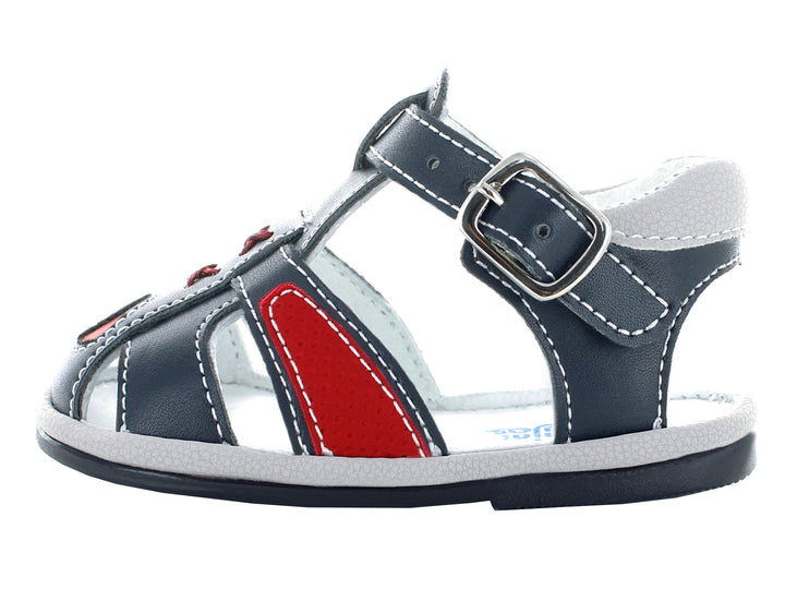 Sandalias infantiles cerradas color azul marino con detalles rojos y cierre de hebilla.