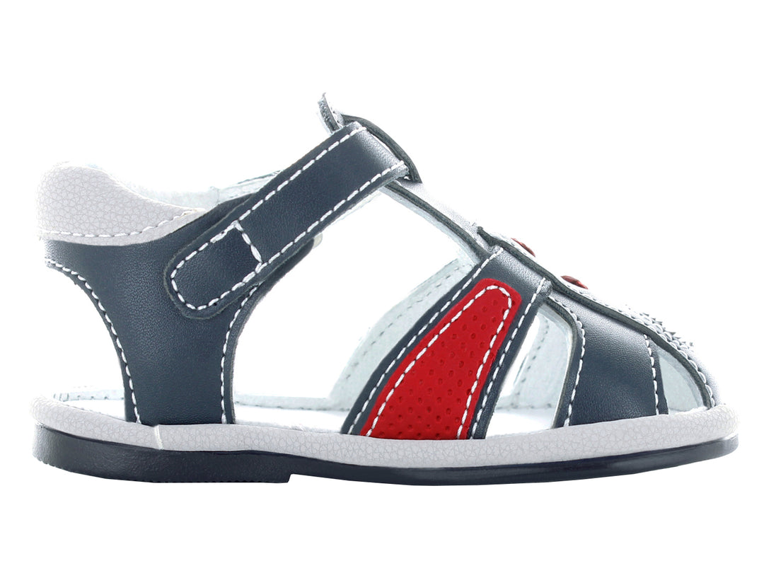 Sandalias infantiles cerradas color azul marino con detalles rojos y cierre de hebilla.