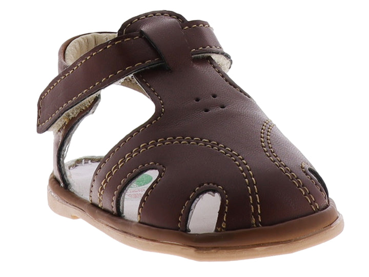 Sandalia infantil color marrón taupe con punta cerrada y correa de ajuste con velcro.