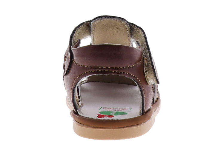 Sandalia infantil color marrón taupe con punta cerrada y correa de ajuste con velcro.