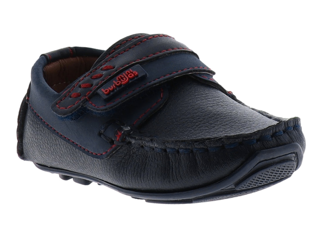 Zapato tipo mocasín color azul marino para niño con costuras decorativas en rojo y cierre de correa con velcro.