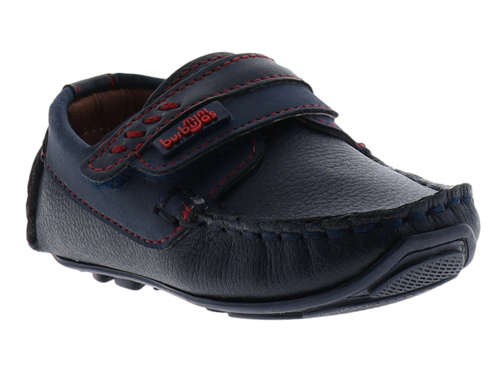 Zapato tipo mocasín color azul marino para niño con costuras decorativas en rojo y cierre de correa con velcro.