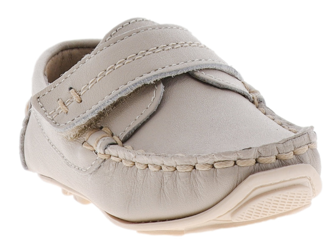 Zapato tipo mocasín para bebé en color hueso con correa de ajuste y costuras decorativas.