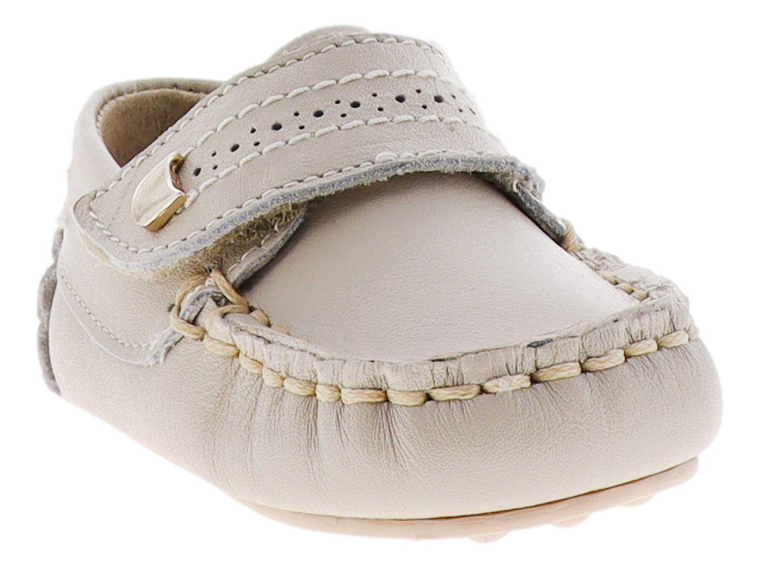 Zapato tipo mocasín para bebé en color hueso con correa ajustable y detalle metálico dorado.