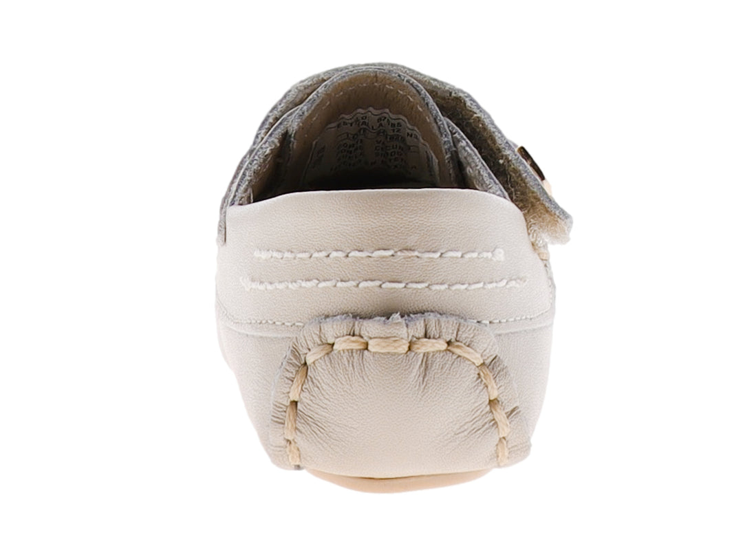 Zapato tipo mocasín para bebé en color hueso con correa ajustable y detalle metálico dorado.