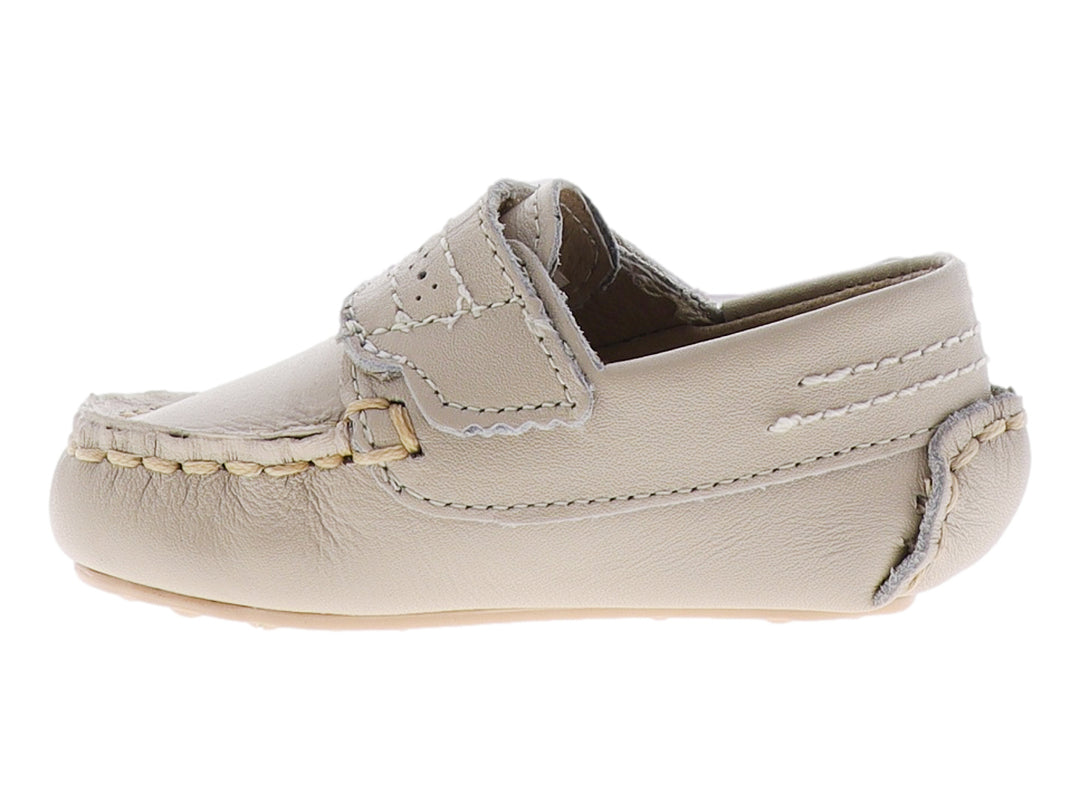 Zapato tipo mocasín para bebé en color hueso con correa ajustable y detalle metálico dorado.