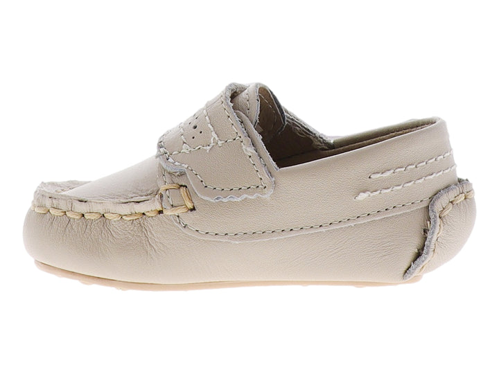 Zapato tipo mocasín para bebé en color hueso con correa ajustable y detalle metálico dorado.