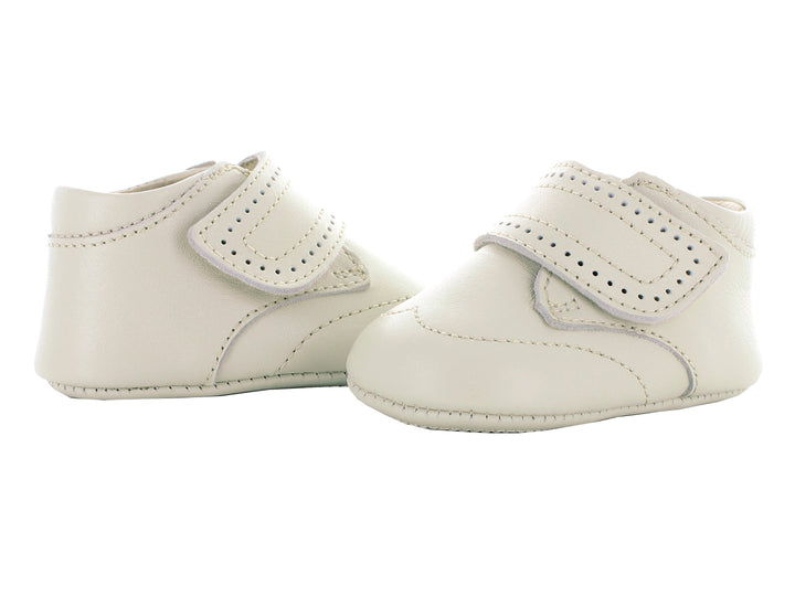Par de zapatos para bebé color hueso con correa ajustable y detalles perforados.