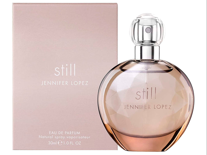 Perfume Jennifer Lopez Still en frasco esférico de vidrio con su caja en tono beige.