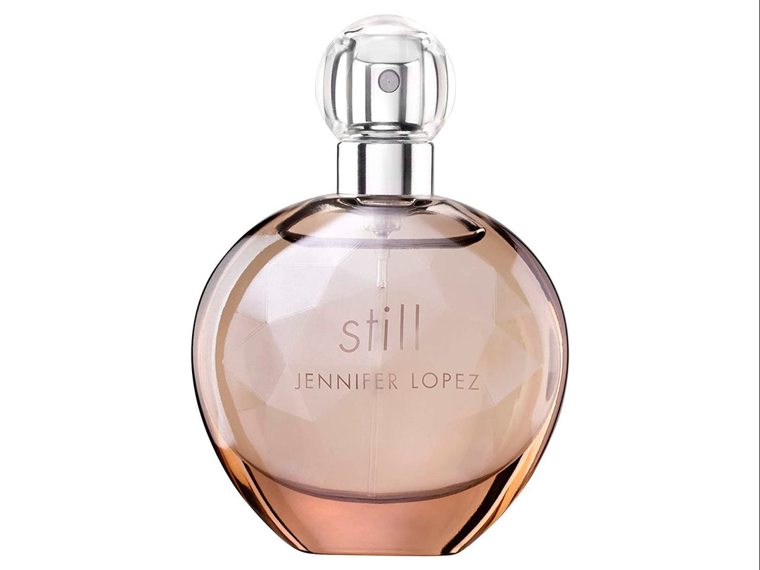Perfume Jennifer Lopez Still en frasco esférico de vidrio con su caja en tono beige.