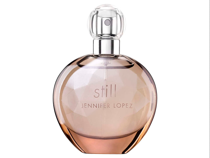 Perfume Jennifer Lopez Still en frasco esférico de vidrio con su caja en tono beige.