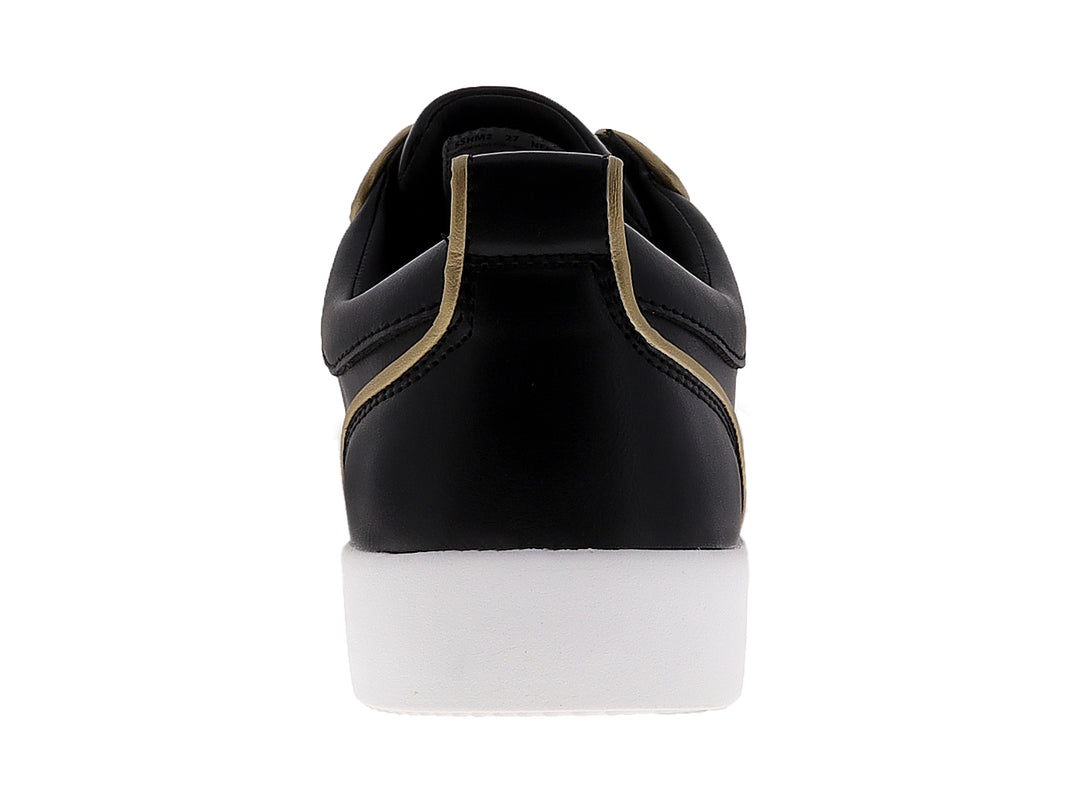 Tenis negros para hombre con tachuelas doradas en la punta y suela blanca.