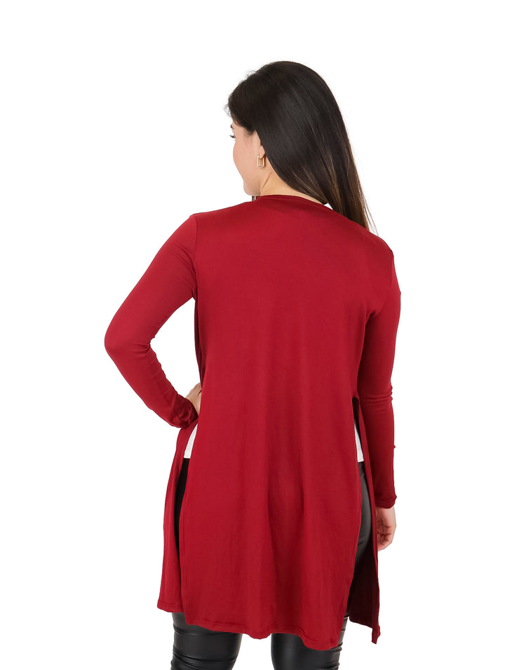 Mujer vistiendo un cardigan largo color vino abierto sobre una blusa blanca y pantalones negros.