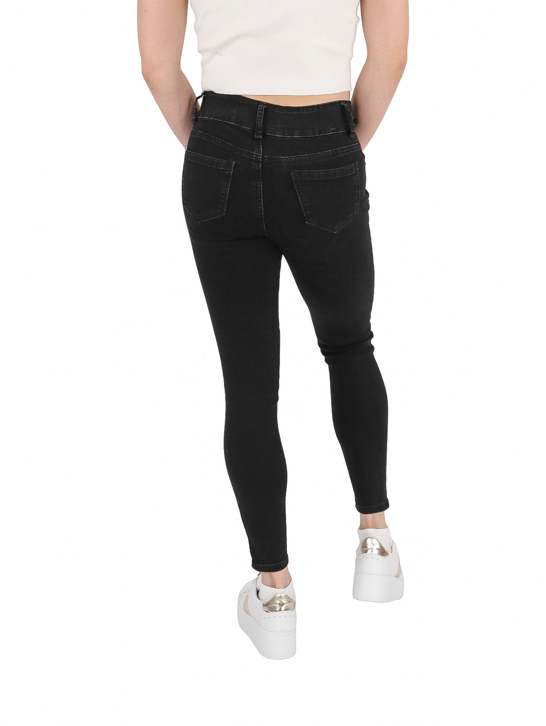 Mujer vistiendo pantalones jeans ajustados de color negro con calzado blanco.