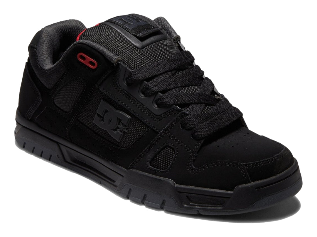Tenis deportivos DC Shoes color negro con suela gruesa y pequeños detalles en rojo.