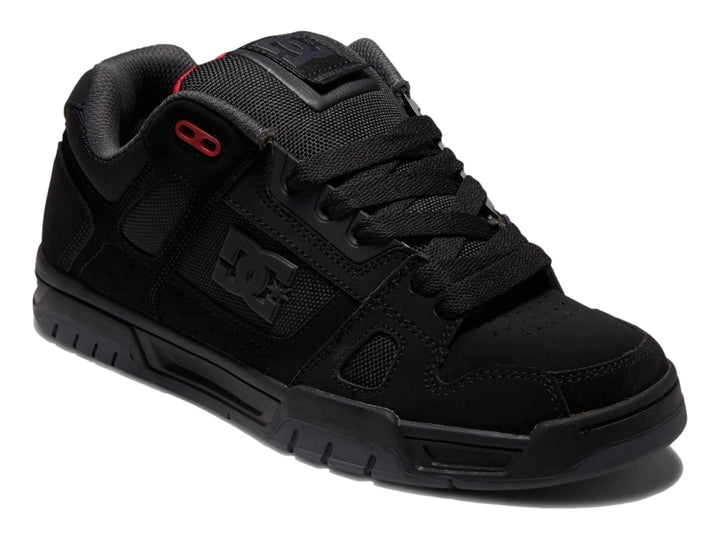 Tenis deportivos DC Shoes color negro con suela gruesa y pequeños detalles en rojo.