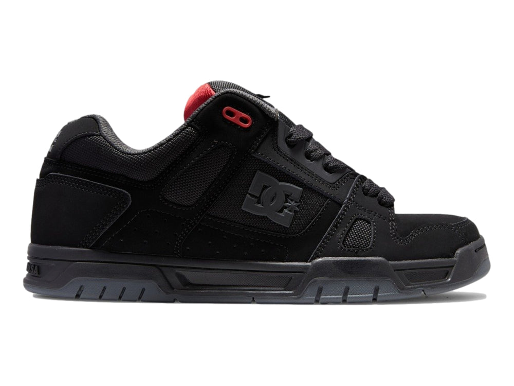 Tenis deportivos DC Shoes color negro con suela gruesa y pequeños detalles en rojo.