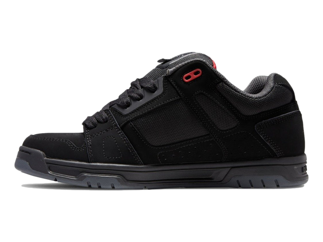 Tenis deportivos DC Shoes color negro con suela gruesa y pequeños detalles en rojo.