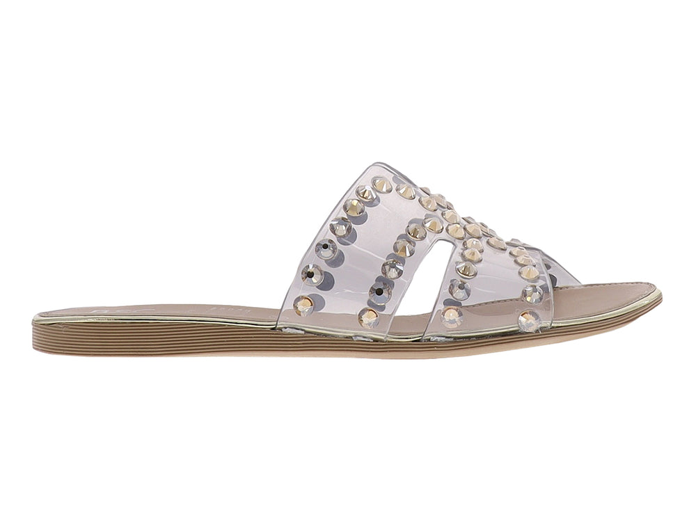 Sandalia con tira transparente y estoperoles dorados sobre suela beige.