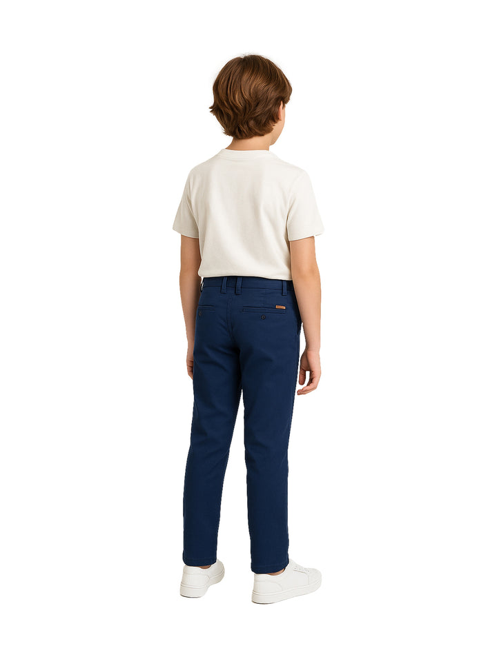 Niño vistiendo pantalón chino de gabardina color azul marino y playera blanca.