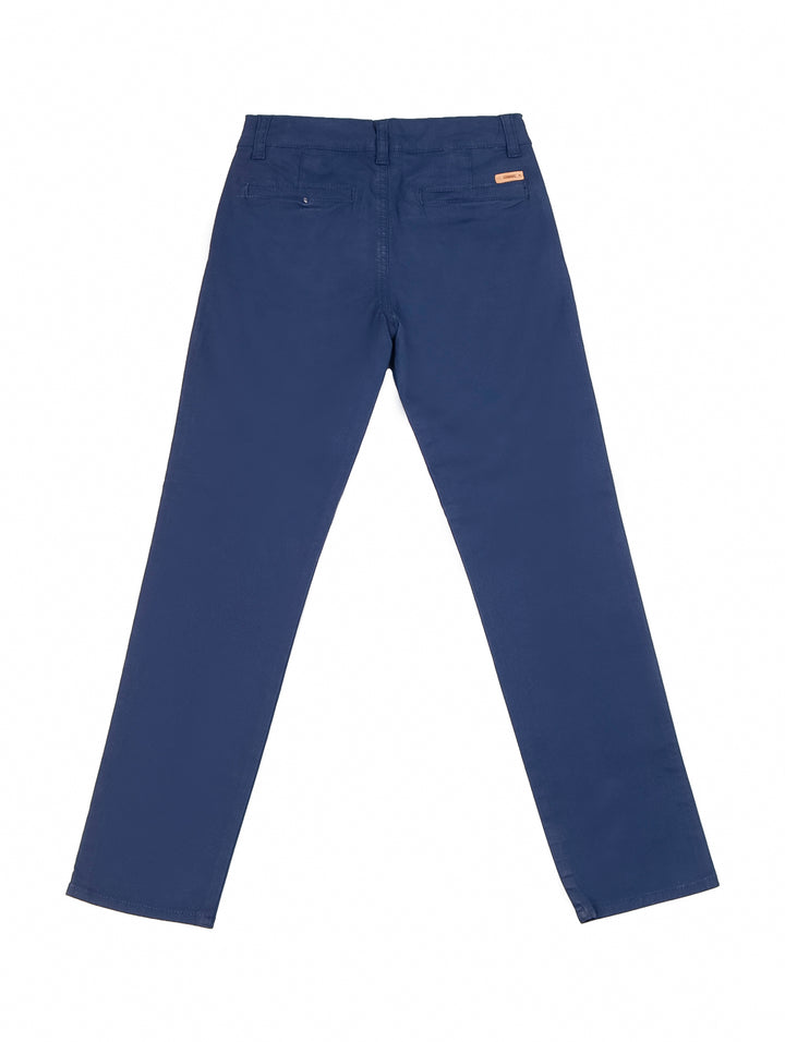 Niño vistiendo pantalón chino de gabardina color azul marino y playera blanca.