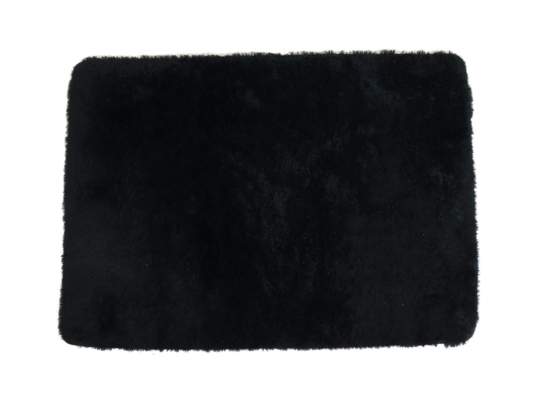 Tapete decorativo rectangular de color negro con textura suave y peluda sobre fondo blanco.