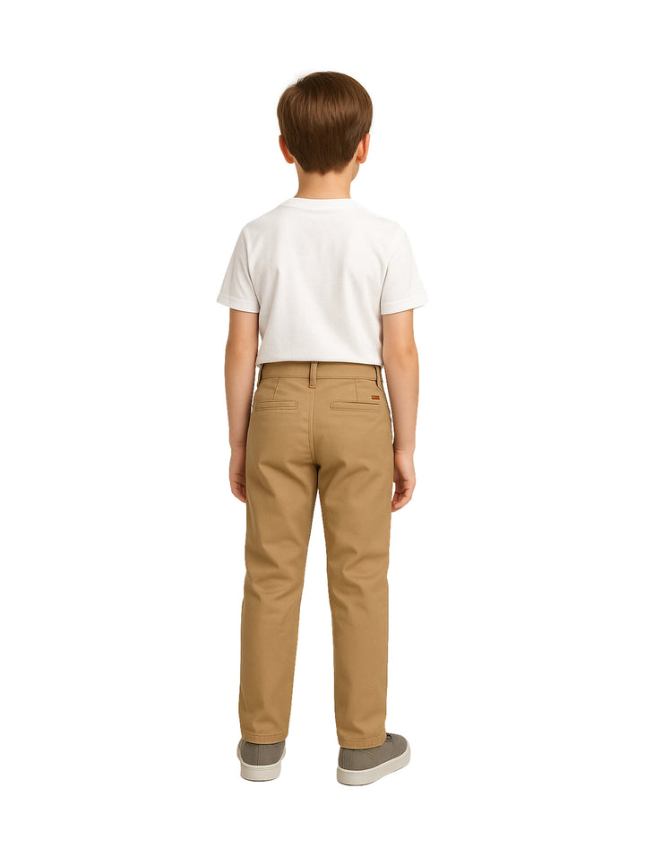 Niño vistiendo pantalón tipo chino de gabardina color beige y camiseta blanca.