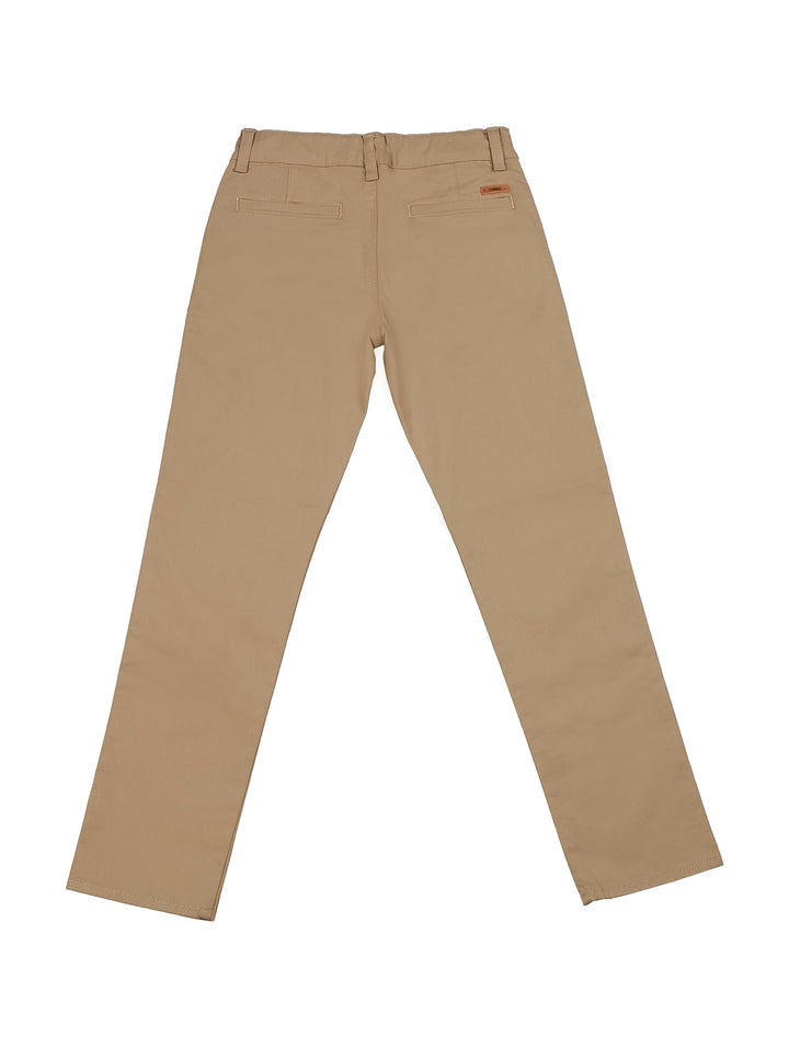 Niño vistiendo pantalón tipo chino de gabardina color beige y camiseta blanca.