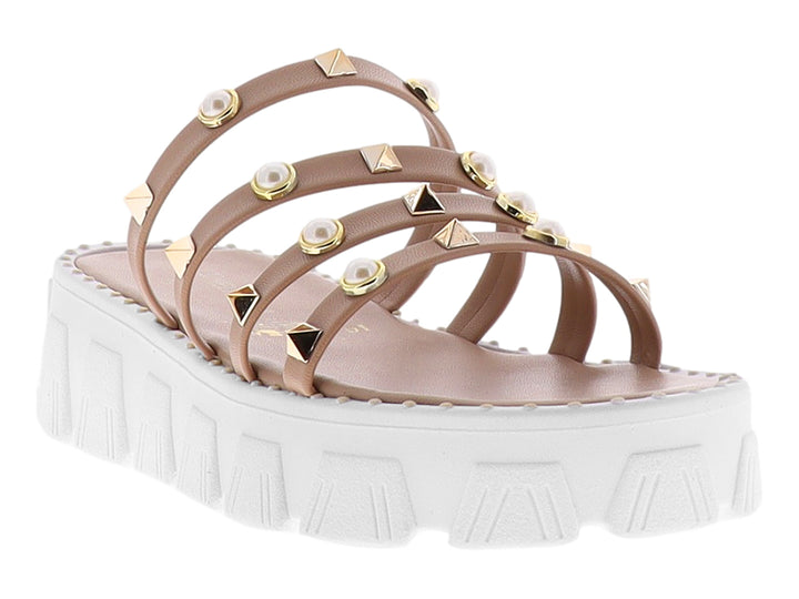 Sandalias de plataforma color maquillaje con tiras adornadas con perlas y tachuelas doradas sobre suela blanca.